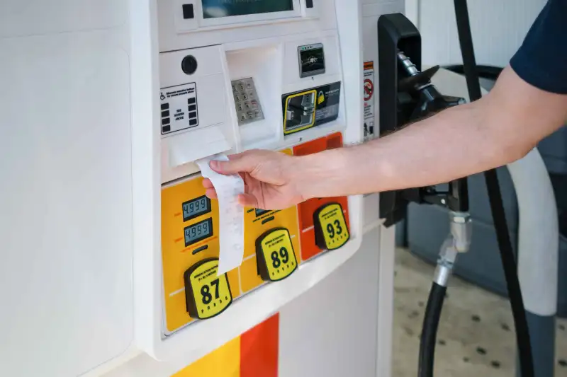 Close-up of unrecognizable man grabbing receipt after purchasing gas at pump