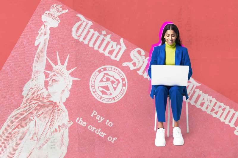 Person sits on stool using laptop in front of an oversized united states treasury refund check