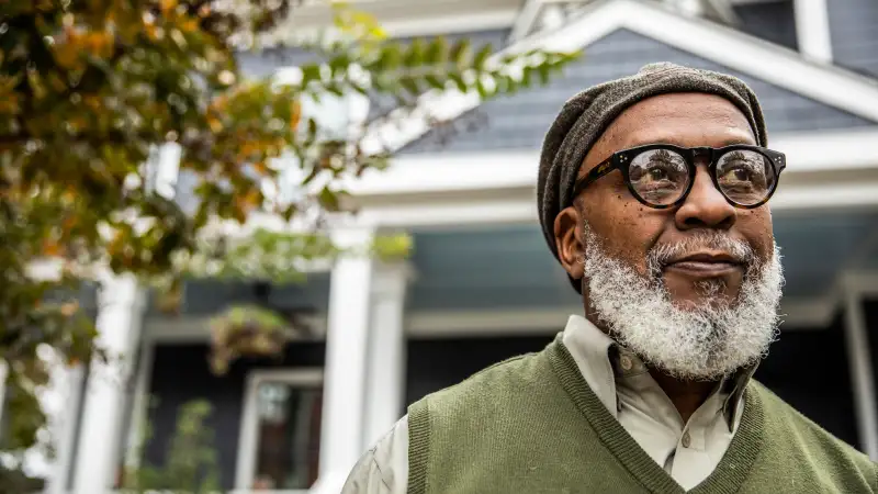 Senior man in front of suburban home