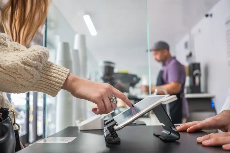 Female Customer Buying Coffee and Placing Signature On Tablet