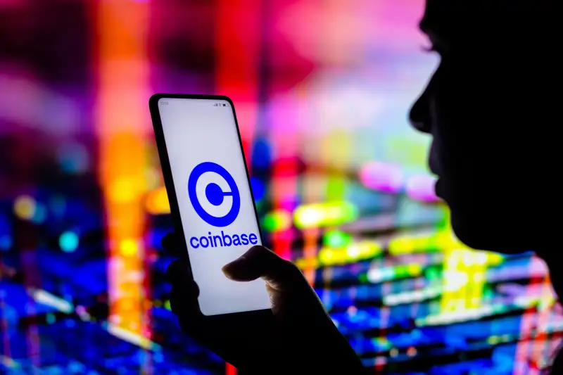 Γυναίκα που κρατά ένα smartphone με λογότυπο Coinbase στην οθόνη