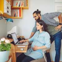 Pregnant Mother and husband working from homeAt home