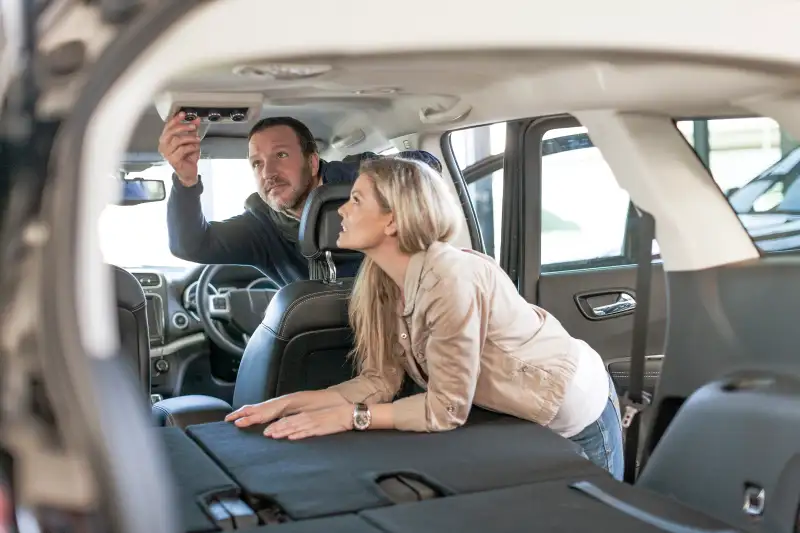 Couple examining new car at car dealership