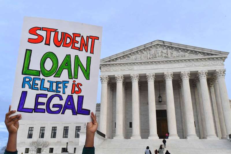 Student in front of supreme court building holding up sign that says student loan relief is legal