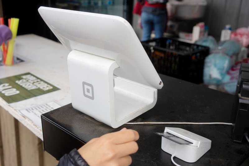A Block (formerly Square Inc.) branded POS stand with a chip card reader is seen processing payments