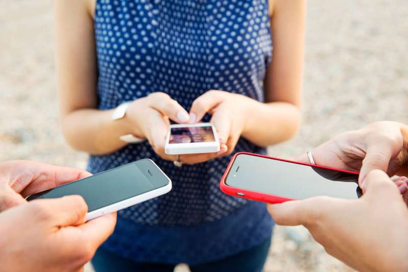 Close-up of three people on their smartphones