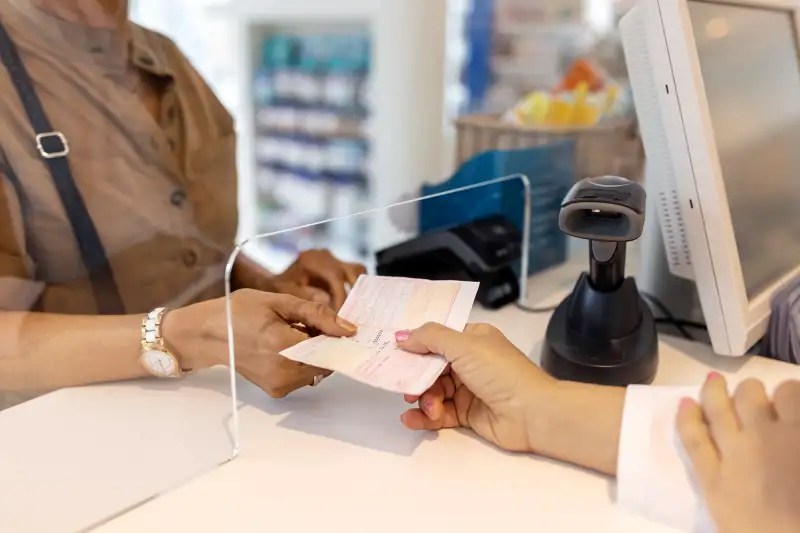 Close-up of a woman hand giving the medicine prescription to  pharmacist in store