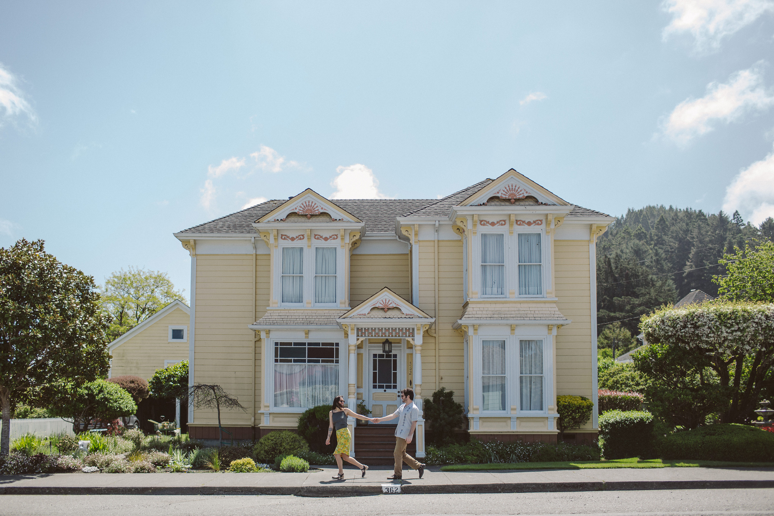 A couple walking down the street, in-front of a victorian house, in Ferndale California