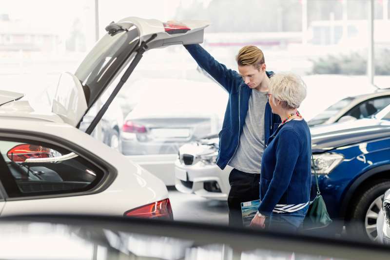 Mother and son examining car in dealership shop