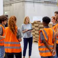 Manager holding a digital tablet discussing something with workers in a warehouse