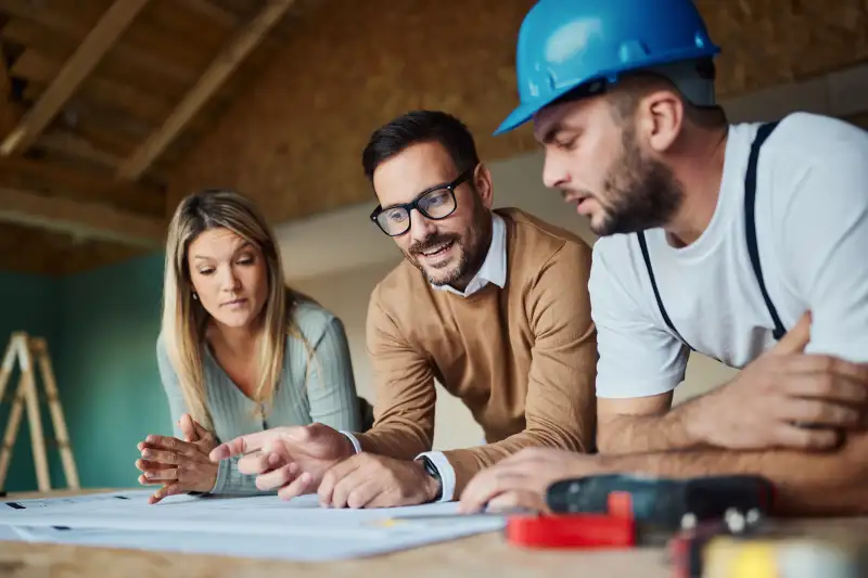 Young couple analyzing blueprints with their construction worker/