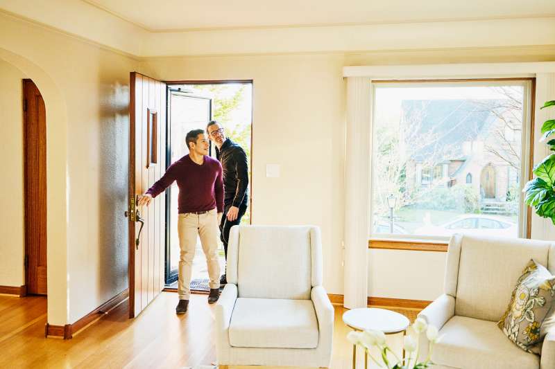 Wide shot of gay couple walking into home for sale during open house