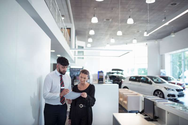 Salesman discussing contract with customer in car dealership