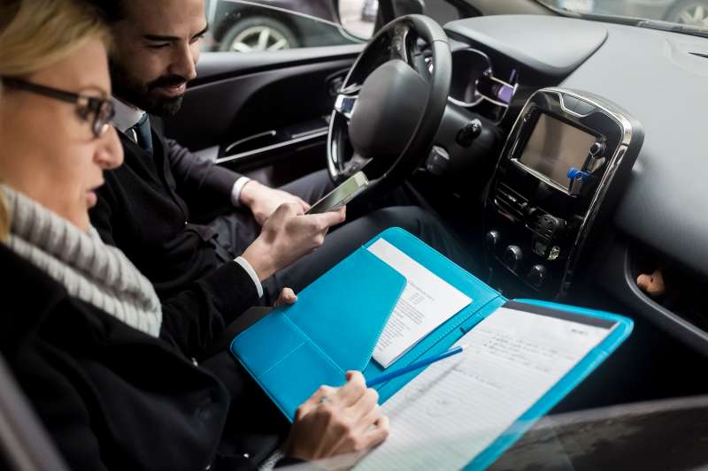 Businessman and businesswoman with documents in car