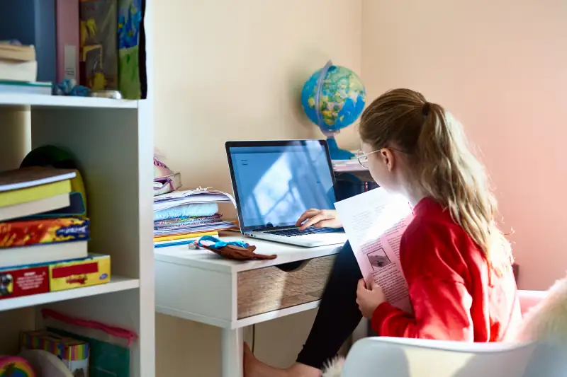 Young girl using laptop in bedroom during lockdown