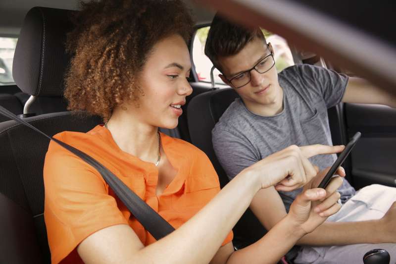 Young couple using smart phone GPS in car