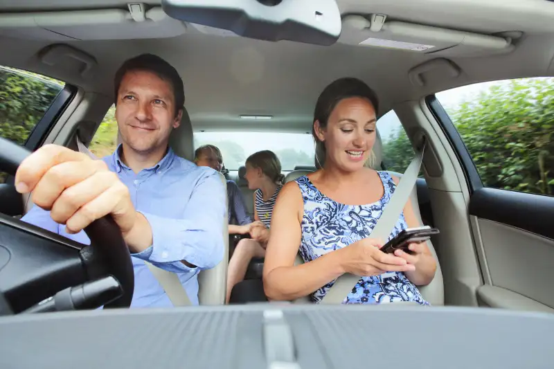 Family in car, mum looking at phone