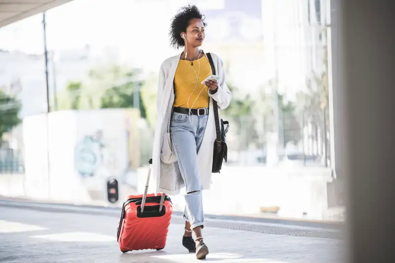 Young woman with cell phone and earphones at the train station