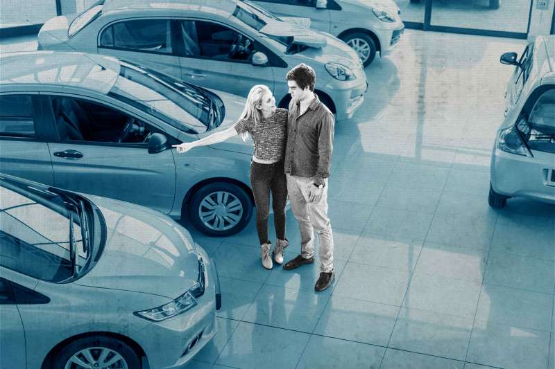 Young couple looking at new cars at car dealership