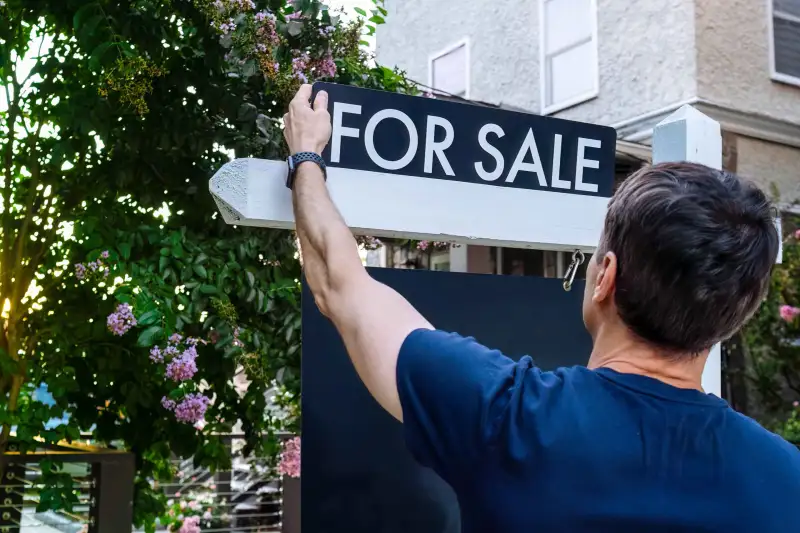 Close-up rear view of real estate agent adjusting for sign in front yard of house