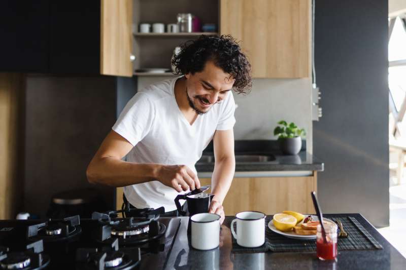 Hispanic young man preparing coffee for breakfast in kitchen at home in Mexico Latin America