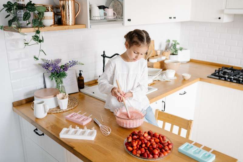 Cute little girl preparing homemade strawberry ice cream at the kitchen.