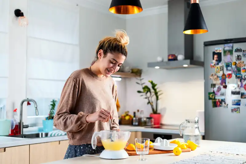 Young beautiful woman making a lemonade in domestic kitchen