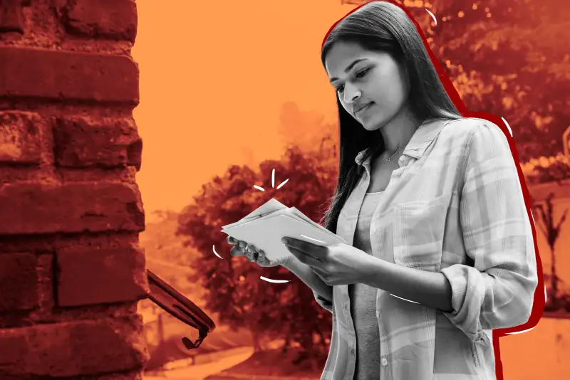 Young woman looking through letters from a mailbox