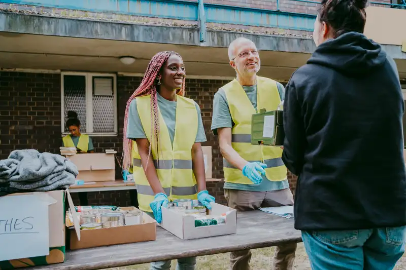 Young woman talking with volunteers wearing reflective clothing in garden