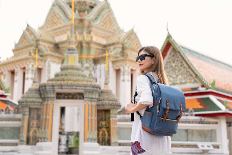 Smiling woman with a backpack in-front of a temple