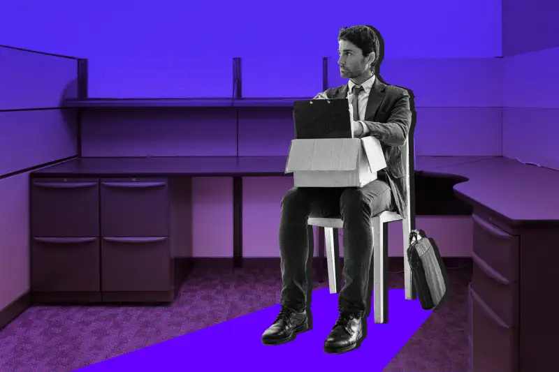 Man looking worried at his office desk with his belongings packed