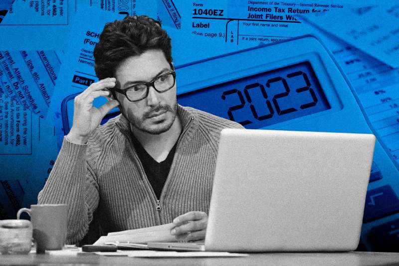 Man looking worried over his laptop with tax forms in the background