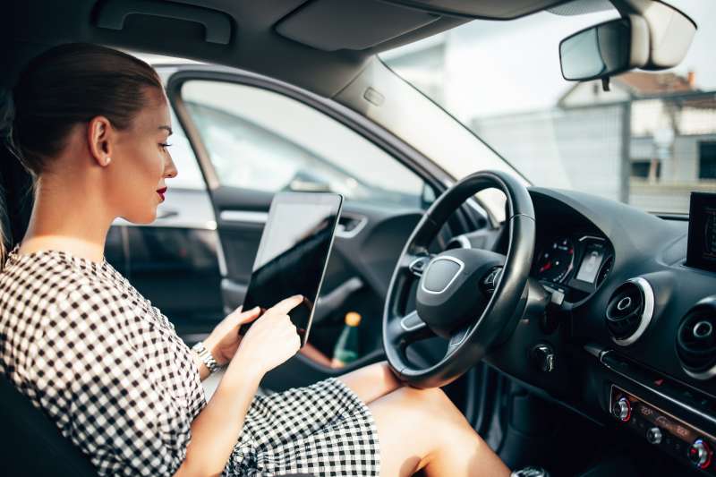 Woman inside a car using a digital tablet