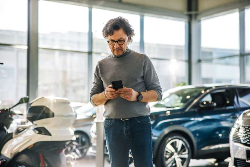 Man looking at his phone in a car dealership
