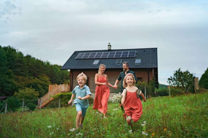 Happy family running near their house with a solar panels.