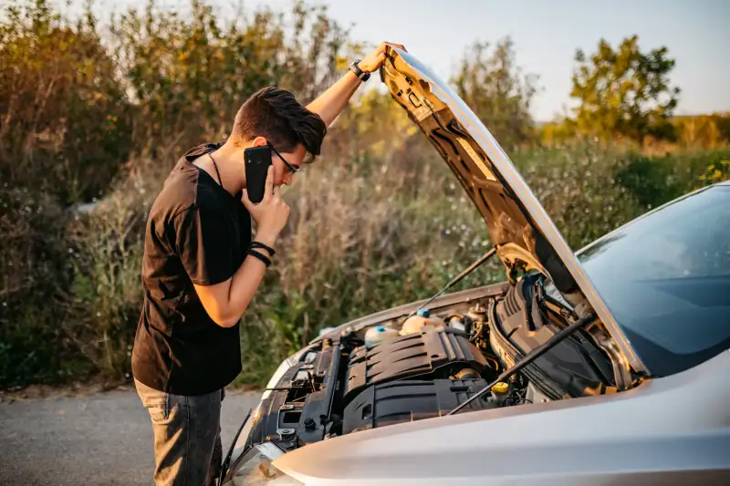 Young handsome Caucasian man had a car breakdown and calling roadside assistance.