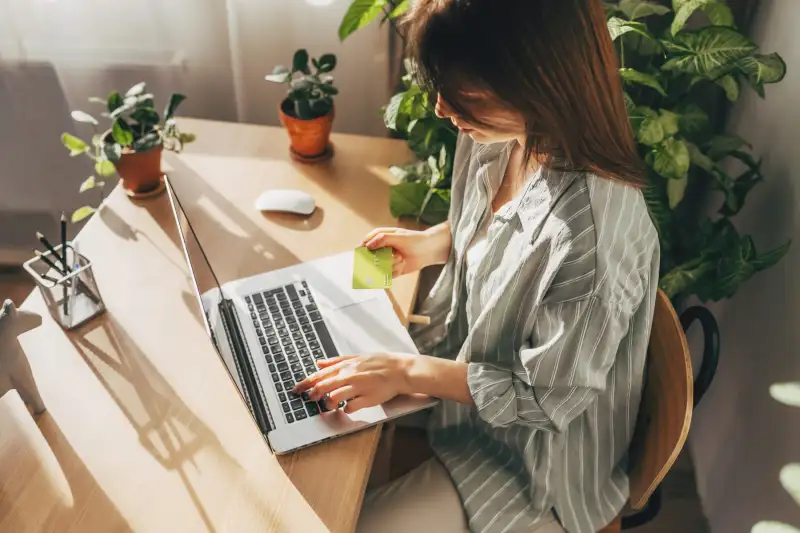 Young woman holding credit card and using laptop computer