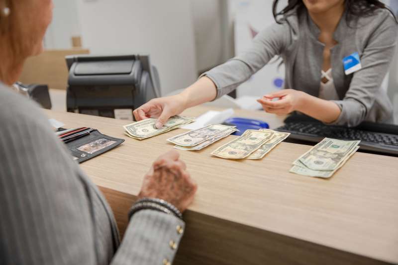 Bank teller counting cash for client at bank branch counter