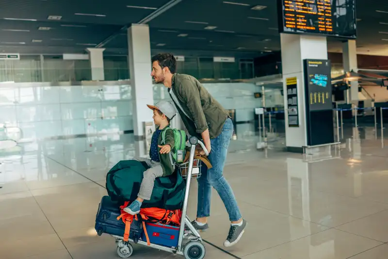 Father and son pushing a luggage cart at the airport