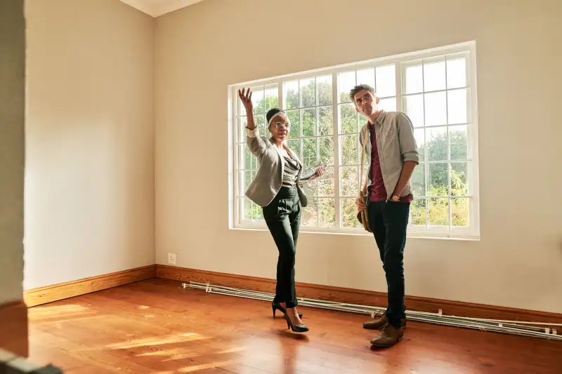 Young female real estate agent talking with a client in the bedroom of house for sale