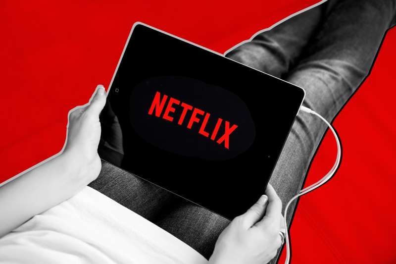 Close-up of a person using a digital tablet with the Netflix logo on the screen
