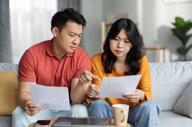 Couple looking over finances sitting on a couch in a living room