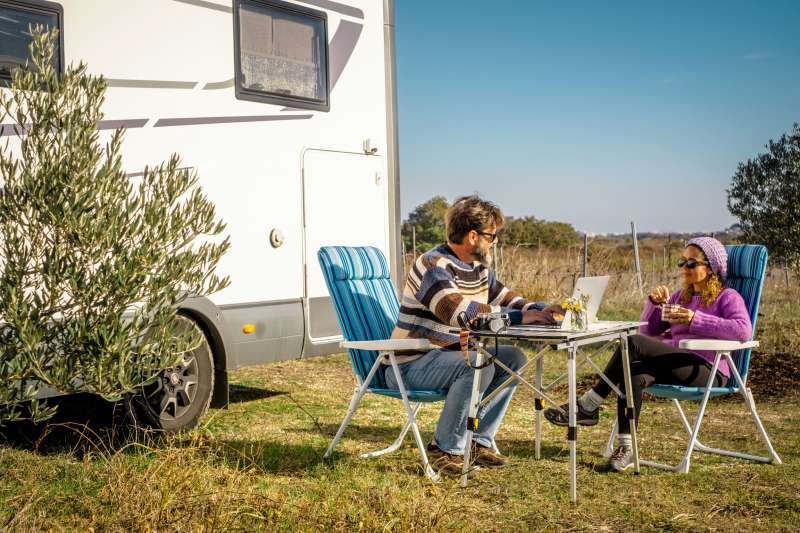 Couple sitting outside in-front of a RV