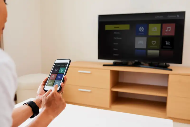 Close-up of young woman is going to watch the movie on TV, and she sitting and connecting her smartphone with programme on TV