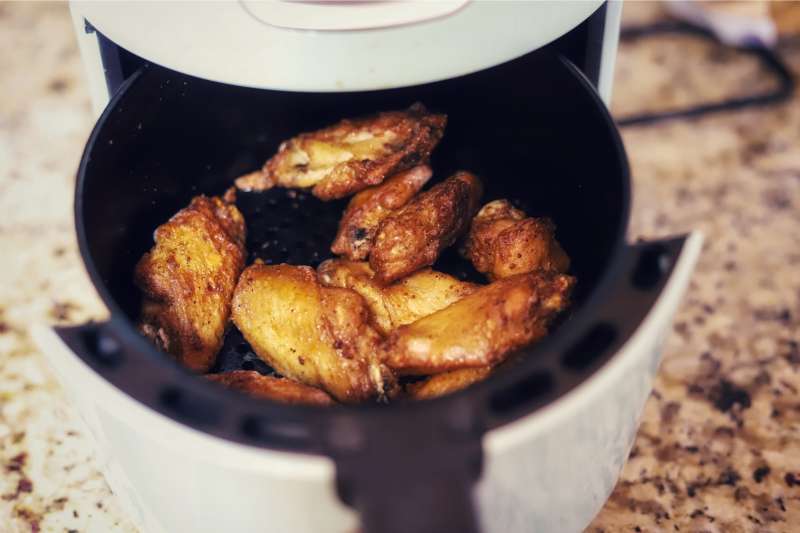 Chicken wings in a air fryer on a kitchen counter