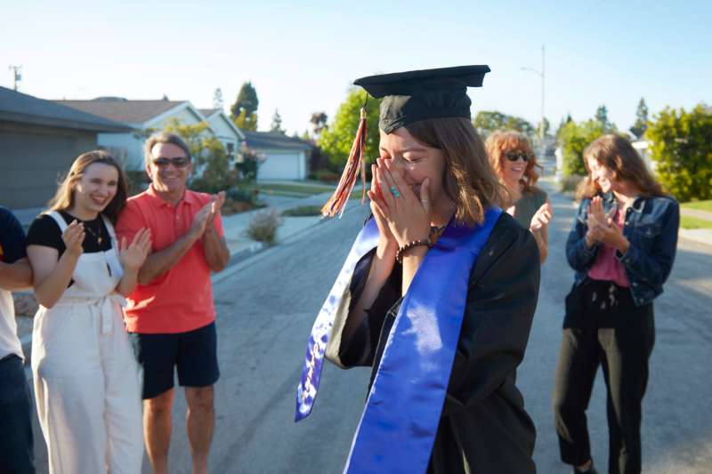 A student wearing a cap and gown with her family on graduation day