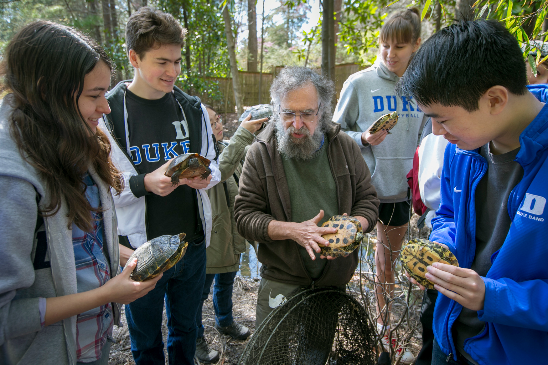 Students and a professor holding a turtle in a outdoor class at Duke University