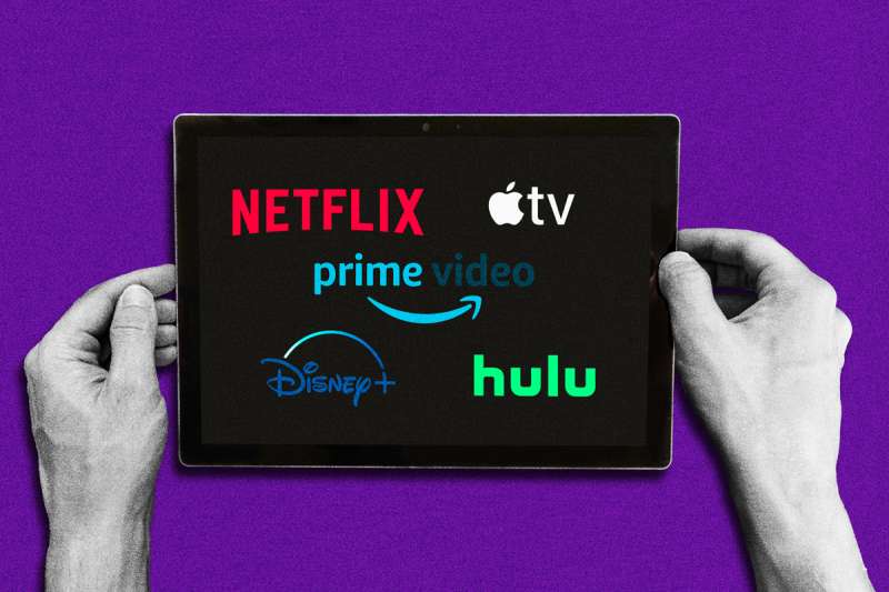 Pair of hands holding a digital tablet with Netflix, Hulu, Appple Tv, Prime Video and Disney Plus logo