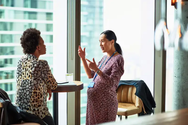 Pregnant Woman talking to a coworker in an office