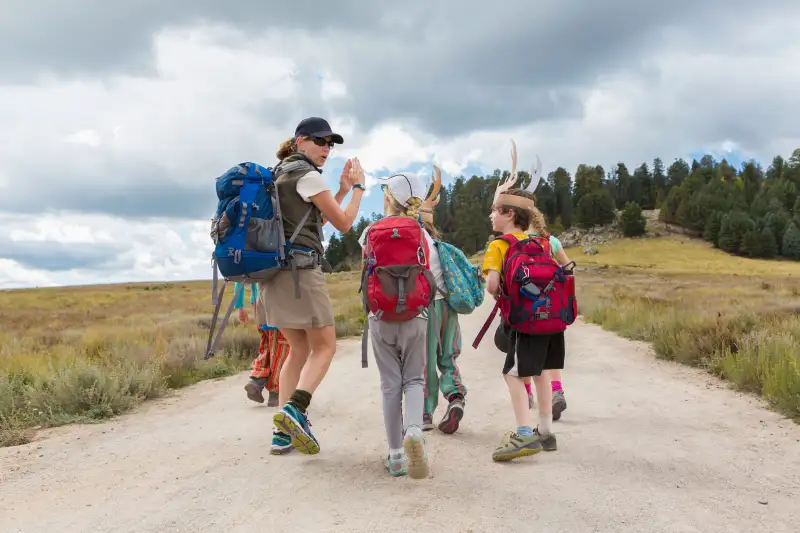 Camp Counselor leading a group of kids into the woods during summer camp